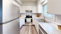 This two-floor residence offers a thoughtfully updated interior with a clean, neutral palette and consistent finishes throughout. The main level opens into a bright, open living area with light-toned luxury vinyl plank flooring, textured ceilings, and white walls that create a welcoming atmosphere. A pass-through window connects the living area to the well-appointed kitchen, which features white cabinetry, marble-style countertops, stainless steel appliances including a refrigerator, electric range, and sink, as well as vinyl plank flooring and a window that brings in natural light. A convenient half bathroom on the main level includes a white vanity, framed mirror, and coordinating fixtures. Upstairs, the bedrooms offer a mix of luxury vinyl plank and plush carpeted flooring, with each room benefiting from windows fitted with blinds that allow for adjustable natural light. One bedroom includes a closet and direct access to the stairway landing. The full bathroom on the upper level is equipped with a shower-tub combination and grab bar. Throughout the space, the design emphasizes practicality and comfort, with ample storage options and a consistent, modern aesthetic that ties each area together cohesively.