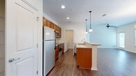 This single-story residence offers a thoughtfully designed layout across a comfortable footprint. The open-concept kitchen and living area serves as the heart of the home, featuring dark hardwood-style flooring, recessed lighting, and a ceiling fan that enhances air circulation. The kitchen is equipped with warm-toned cabinetry, granite countertops, stainless steel appliances—including a refrigerator, electric range, and microwave—and a peninsula island with an undermount sink illuminated by pendant lighting. A set of double doors provides additional storage adjacent to the kitchen.

The living area benefits from natural light through multiple windows with blinds, and access to an outdoor area via a glass door. Both bedrooms are carpeted and feature vaulted ceilings, adding a sense of spaciousness. Each bedroom is served by a walk-in closet outfitted with wire shelving systems. The two bathrooms are finished with tile flooring, granite-topped vanities with warm wood cabinetry, and tub-shower combinations. A dedicated laundry room accommodates a full-size washer and dryer with additional wire shelving for storage, completing the functional layout of this well-organized residence.