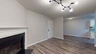Located at 6782–6786 Buffington Road in Union City, Georgia, this single-story unit presents a thoughtfully updated interior with a neutral color palette and a cohesive blend of modern and functional design elements throughout.

The living area is a welcoming, open space anchored by a classic white-mantled fireplace and finished with durable wood-look plank flooring in a warm gray tone. A contemporary branching light fixture adds a stylish focal point overhead, while a textured ceiling provides depth. A sliding glass door introduces natural light and provides outdoor access, and a hallway connects the main living space to the rest of the unit.

The galley-style kitchen is well-appointed with crisp white cabinetry featuring matte black hardware, gray laminate countertops, a subway tile backsplash, and wood-look flooring. Black appliances, including a refrigerator, range, and dishwasher, offer a clean contrast to the light cabinetry.

The bedrooms are carpeted for comfort, each featuring ceiling fans, windows with blinds that allow natural light, and neutral walls offering a calm, restful atmosphere.

The bathrooms are cleanly finished with wood-look flooring, white vanity cabinetry, gray countertops, matte black fixtures, and tub-shower combinations, delivering a polished, updated look throughout.
