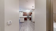 Located at 5400 Chenonceau Blvd in Little Rock, AR, this thoughtfully designed one-bedroom, one-bathroom residence offers a well-utilized single-floor layout. The open-concept living and kitchen area serves as the heart of the home, featuring rich dark wood cabinetry, granite countertops, stainless steel appliances — including a range, microwave, and refrigerator — and a peninsula with pendant lighting that doubles as a breakfast bar. Hardwood-style luxury vinyl plank flooring runs throughout the main living areas, complemented by a ceiling fan and a chandelier that add warmth and character. Large windows and a glass-panel exterior door flood the living area with natural light and offer views of the surrounding greenery. Crown molding and structured column details lend an architectural polish to the space. The bedroom is comfortably sized, finished with plush carpet, a ceiling fan, and a natural light-filled window. The bathroom features tile flooring and connects to a dedicated laundry area equipped with a top-load washer. A separate closet provides additional storage. This residence combines functional design with refined finishes throughout.