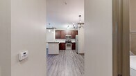 Located at 5400 Chenonceau Blvd in Little Rock, AR, this thoughtfully designed one-bedroom, one-bathroom residence offers a well-utilized single-floor layout. The open-concept living and kitchen area serves as the heart of the home, featuring rich dark wood cabinetry, granite countertops, stainless steel appliances — including a range, microwave, and refrigerator — and a peninsula with pendant lighting that doubles as a breakfast bar. Hardwood-style luxury vinyl plank flooring runs throughout the main living areas, complemented by a ceiling fan and a chandelier that add warmth and character. Large windows and a glass-panel exterior door flood the living area with natural light and offer views of the surrounding greenery. Crown molding and structured column details lend an architectural polish to the space. The bedroom is comfortably sized, finished with plush carpet, a ceiling fan, and a natural light-filled window. The bathroom features tile flooring and connects to a dedicated laundry area equipped with a top-load washer. A separate closet provides additional storage. This residence combines functional design with refined finishes throughout.