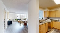 Located at 10301 Grosvenor Pl in Rockville, MD, this well-appointed 1-bedroom, 2-bathroom residence offers a thoughtfully designed single-floor layout with an inviting, light-filled atmosphere throughout. Light wood-style flooring flows seamlessly across the living areas, complementing the neutral color palette and clean architectural lines.

The open-plan living and dining area is bathed in natural light from large windows that frame serene treetop and neighborhood views, with access to a private balcony. The kitchen is outfitted with warm maple cabinetry, granite countertops, stainless steel appliances including a full-size refrigerator, and ample counter and storage space arranged in an efficient layout.

The spacious primary bedroom offers generous square footage, large windows with outdoor views, and direct access to one of the two bathrooms. Both bathrooms feature granite-topped vanities with maple cabinetry and clean tile finishes. The hallway connects the rooms with ease, providing additional functional flow throughout the residence.

A secondary flexible living space with large windows and balcony access serves well as a home office or sitting room. The overall ambiance is bright, modern, and welcoming, making this Rockville residence a polished and comfortable place to call home.