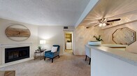 Located in Lakewood, Colorado, this well-appointed 2-bedroom, 1-bathroom unit offers a comfortable and functional single-floor layout. The carpeted living room serves as the heart of the home, centered around a classic fireplace and sliding glass doors that open to a private patio with views of lush greenery. The open-concept dining area flows seamlessly from the living space and connects directly to the kitchen via a peninsula with light stone countertops, allowing for easy interaction between rooms. A ceiling fan overhead adds comfort to the dining area. The galley-style kitchen features warm wood cabinetry, light wood-look flooring, a full suite of white appliances including a range, microwave, dishwasher, and refrigerator, along with ample counter and storage space. The primary bedroom is generously sized, offering plush carpet, a textured ceiling, and a walk-in closet. A second bedroom provides additional flexibility for guests or a home office. The full bathroom includes a tub-shower combination, a wide vanity with an extended mirror, and bright overhead lighting. A dedicated utility room houses in-unit washer and dryer connections, adding everyday convenience to this well-rounded Lakewood residence.