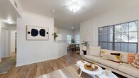 This single-floor, 3-bedroom, 1-bathroom home offers a thoughtfully designed layout that maximizes functionality and comfort. The bright living room features warm hardwood-style flooring, crown molding, a ceiling fan, and multiple windows dressed with horizontal blinds that filter in generous natural light. A pass-through connects the living area to the kitchen, creating an open, airy feel throughout the main living space.

The galley-style kitchen is outfitted with warm wood cabinetry, white countertops, and black appliances including a refrigerator, range, microwave, and dishwasher. It opens conveniently toward the dedicated laundry room, which houses a full-sized washer and dryer alongside built-in shelving.

The adjacent dining room is bright and inviting, with large windows offering views of lush greenery outside — an ideal setting for everyday meals or entertaining.

The primary bedroom features plush carpeting, a ceiling fan, and a walk-in closet. The additional bedrooms are comfortably sized, each with closet space. The shared bathroom includes a double-sink vanity with warm wood cabinetry, a large mirror, and Hollywood-style lighting.

Throughout the home, a neutral color palette and consistent flooring create a cohesive, modern aesthetic that is both welcoming and versatile.