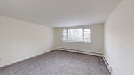 Located at 101 W Baltimore Ave in Lansdowne, PA, this two-bedroom, one-bathroom residence offers a well-organized single-floor layout designed for comfortable everyday living. The floor plan flows logically from a welcoming hallway through the living and dining areas and into the private sleeping quarters.

The living room is generously proportioned, featuring neutral carpet, crisp white walls, and a wide bank of windows that flood the space with natural light while offering views of the surrounding greenery. Baseboard heating runs throughout the carpeted rooms, ensuring consistent warmth. The adjacent kitchen is functional and well-equipped, featuring warm honey-toned wood cabinetry, granite-style countertops, tile flooring, and white appliances including a dishwasher, electric range, and refrigerator.

Both bedrooms are carpeted and bathed in soft, neutral tones. The primary bedroom is a comfortable size, while the second bedroom also benefits from natural light via a window with blinds. Notably, the unit includes four closets, providing exceptional storage throughout. The bathroom features a tub-shower combination dressed in elegant rectangular stone-look tiles with a decorative mosaic border accent, adding a refined touch. The layout is completed by a connecting hallway with a chandelier fixture visible from the secondary bedroom.