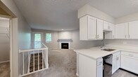 Located at 200 Lake Forest Blvd in Kalamazoo, Michigan, this two-story, 3-bedroom, 2-bathroom home offers a practical and comfortable layout spread across two floors. The main level features an open-concept kitchen and living area, where white shaker-style cabinetry, light countertops, and black appliances — including a range, microwave, and refrigerator — define the kitchen space. Light wood-style flooring runs through the kitchen, which flows seamlessly into the carpeted living room. A fireplace serves as the focal point of the living room, complemented by natural light from multiple windows. A staircase with a white banister connects the two levels. The upper floor houses all three bedrooms, each finished with soft carpet and neutral-toned walls. The generously sized primary bedroom offers ample space and natural light from a window with outdoor views. Two full bathrooms feature white vanities with light countertops, wood-look tile flooring, and tub-shower combinations with tiled surrounds. Three hallways provide smooth circulation throughout the home, and a dedicated closet adds convenient storage. The overall aesthetic is clean and neutral, making for a move-in ready home.