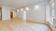 Located at 229 Willett Ave in Port Chester, NY, this thoughtfully designed one-bedroom, one-bathroom residence offers a clean, modern aesthetic across a well-utilized single floor. Light-toned hardwood flooring runs continuously throughout, creating a cohesive and airy feel in every room. The open-concept kitchen and living area serves as the heart of the home, showcasing a striking center island with a slatted wood base and white quartz countertop, complemented by a matte black faucet. White shaker-style cabinetry lines the walls alongside a marble-effect tile backsplash, and stainless steel appliances — including a French door refrigerator and slide-in range — complete the chef-ready space. Recessed and pendant lighting add both function and style. The living area is bright and open, with recessed lighting and a clean, neutral palette. The bedroom is a comfortable, well-proportioned retreat featuring a window with neighborhood views and natural light. A dedicated walk-in closet offers extensive built-in shelving and hanging rods for generous storage. The bathroom presents a spa-like finish with large-format stone-look tiles, a floating vanity with backlit mirror, matte black fixtures, and a walk-in shower.