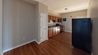 This single-floor residential unit offers a thoughtfully designed layout that balances comfort and functionality. The living area is a standout feature, showcasing rich hardwood flooring and a charming bay window that frames outdoor views and fills the room with natural light, creating a warm and inviting atmosphere.

The kitchen is efficiently organized with warm-toned wooden cabinetry, a full suite of black appliances including a refrigerator, stove, and microwave, and a sink set into a practical countertop. The hardwood flooring continues seamlessly into this space, and a paneled white door provides convenient access to an adjoining area.

The bedrooms are finished with plush wall-to-wall carpeting in a neutral tan tone, offering a soft and comfortable underfoot feel. Each bedroom benefits from windows that allow natural light to permeate the space while providing views of the surrounding neighborhood. The neutral, greige wall tones throughout the unit create a cohesive and calming palette that complements both the carpeted and hardwood-floored areas.

White trim and baseboards provide clean contrast throughout the unit, enhancing the overall sense of brightness and polish. The open, uncluttered layout across all rooms offers versatile potential for a variety of furniture arrangements and personal styles.