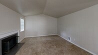 Located on Vineyards Lane NE in Bremerton, Washington, this two-bedroom, two-bathroom single-floor home offers a comfortable and functional layout with thoughtful design details throughout. The open kitchen and living area serves as the heart of the home, where white cabinetry, light stone-look countertops, a double sink, and black appliances — including a refrigerator and electric range — create a clean, practical kitchen space. A peninsula counter connects the kitchen to the living area, which features carpet flooring, a ceiling fan, and a classic tiled fireplace with a white mantel that adds warmth and character to the room. Natural light filters in through vertical-blind-covered windows. The primary bedroom stands out with vaulted ceilings that lend an airy, spacious feel, along with carpeted floors and a window. The second bedroom is generously sized with plush carpet and a large window overlooking greenery outside. A dedicated closet provides additional storage. Both bathrooms are finished with tile flooring, white vanity cabinetry, stone-look countertops, and tub/shower combinations. The neutral color palette and soft carpet throughout the bedrooms and living areas create a calm, cohesive ambiance across the entire home.