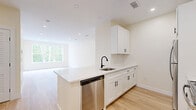 Located at 226 East Rd in Meriden, CT, this thoughtfully designed one-bedroom, one-bathroom unit offers a clean, modern aesthetic throughout its efficiently laid-out single floor. Light-toned hardwood flooring flows seamlessly across all living areas, creating a bright and cohesive feel. The open-concept kitchen and living room serves as the heart of the unit, where white shaker cabinets with matte black hardware, quartz countertops, a peninsula with an undermount sink, and stainless steel appliances—including a refrigerator, range, and dishwasher—combine both style and functionality. Recessed lighting illuminates the living area, which benefits from generous natural light through large windows. The bedroom is a well-proportioned retreat featuring a wide window overlooking lush, mature woodland, providing a serene and private atmosphere. A glass-panel door opens directly to a private balcony framed by a dark metal railing, offering peaceful tree-lined views. The full bathroom is finished with white shaker cabinetry, quartz countertops, a subway tile tub/shower surround, and a backlit vanity mirror. A dedicated closet and hallway complete the layout, making this a well-appointed and functional living space.