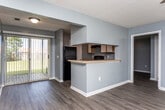 Located at 100 Tallokas Ct in Leesburg, Georgia, this single-floor unit offers a practical and cohesive layout finished in cool gray tones throughout. Wood-look plank flooring runs consistently across the living areas and bedrooms, complemented by crisp white baseboards and textured ceilings.

The open living area is bright and well-proportioned, featuring a ceiling fan and vertical blinds that provide access to natural light. It connects seamlessly to the kitchen via a pass-through counter with a raised breakfast bar. The kitchen is equipped with light wood cabinetry trimmed in white, a full suite of black appliances including a refrigerator and electric range, a stainless steel sink, and ample counter space along an L-shaped layout.

The bedrooms are generously sized, each outfitted with a ceiling fan and large windows that invite natural light. Several bedrooms include closets—some with sliding doors and others with hinged doors offering open rod storage. The unit includes two bathrooms: one full bath with a tub/shower combination, single vanity, and wood-look flooring, and a second bathroom with a pedestal sink, toilet, and a well-lit vanity mirror. The consistent gray wall palette and clean finishes create a cohesive, move-in-ready atmosphere throughout the entire space.