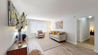 This well-appointed single-floor residence offers a thoughtfully designed layout that balances comfort and functionality. The living room serves as the heart of the unit, featuring light hardwood-style flooring, crisp white walls, and a large window dressed with horizontal blinds that allows natural light to fill the space. The open feel is enhanced by clean lines and neutral tones throughout.

The galley-style kitchen is efficiently organized with floor-to-ceiling dark gray shaker cabinets, white quartz countertops, a subway tile backsplash, stainless steel appliances, and a built-in sink. A set of bi-fold closet doors at the end of the kitchen provides additional storage. Adjacent to the kitchen, a dedicated dining area accommodates a full-sized table and benefits from its own window and ceiling light fixture.

The two bedrooms are carpeted and generously sized, each featuring windows that invite natural light. The bathrooms maintain a consistent modern aesthetic, with dark gray vanity cabinetry, white countertops, and light wood-style flooring. One bathroom includes a shower-tub combination. The overall palette of soft whites and grays creates a clean, cohesive ambiance throughout the space.