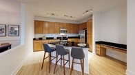 This single-floor residence offers a thoughtfully designed layout that balances comfort and modern style. The living room is a welcoming focal point, featuring light hardwood flooring, crown molding, a ceiling fan, and multiple windows that invite natural light. Contemporary furnishings, including a tufted sofa and bold accent chairs, complement the clean, neutral palette of the space.

The kitchen is well-equipped for cooking and entertaining, boasting warm wood cabinetry, dark granite countertops, stainless steel appliances including a gas range and built-in microwave, and a peninsula with bar seating for three. Track lighting overhead ensures the space is bright and functional. Adjacent to the kitchen, the dining area features hardwood flooring, crown molding, chair-rail detailing, and a pendant light fixture above a wood dining table, creating an intimate setting for meals.

The two bedrooms offer plush carpeting, ample natural light, and generous storage. Each room carries a calm, restful ambiance with tasteful décor accents.

The residence includes two bathrooms: a full bath with a dual-sink vanity, warm wood cabinetry, a tub-shower combination, and tile flooring; and a second bath with a glass-enclosed shower stall and single vanity. Both bathrooms are finished in crisp, neutral tones for a clean, polished look.