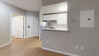 Located at 8710 Research Dr in Charlotte, NC, this single-floor unit offers three bedrooms and two bathrooms with a clean, modern aesthetic. The kitchen is designed with white shaker-style cabinetry, quartz-style countertops, a subway tile backsplash, a stainless steel sink, and a pass-through counter that opens to the main living area, creating an open and connected feel. A stainless steel refrigerator and electric range complete the functional cooking space. Light wood-tone flooring runs throughout the unit, providing a cohesive and bright atmosphere. The bedrooms are finished with neutral gray walls and white trim; the primary bedroom offers a comfortable footprint with a closet, while the secondary bedrooms each feature natural light from windows with blinds and built-in closet storage. The two bathrooms include a full bath with a tub/shower combo, grab bar, and light wood-tone flooring, as well as a vanity bath with a speckled quartz countertop, white cabinetry, and a large mirror. Six-panel white interior doors and consistent neutral wall tones contribute to a clean, uniform design throughout the space.