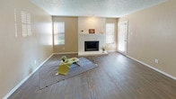 This single-story unit at 357 E Corporate offers a well-organized layout with distinct living, dining, kitchen, bedroom, and bathroom areas. The living room is a standout space, featuring dark hardwood-style flooring, neutral beige walls, a textured ceiling, and a white-painted brick fireplace as the focal point. Multiple windows with blinds allow natural light to fill the room, creating a bright and welcoming atmosphere. A separate entry door is conveniently accessible from the living area.

The kitchen is designed with functionality in mind, featuring a peninsula with a dark countertop, white cabinetry, a tile mosaic backsplash, and overhead cabinets for ample storage. The adjacent dining area benefits from the same dark flooring and is illuminated by a ceiling fan light fixture. The layout provides an open connection between the kitchen and dining spaces.

Bedrooms are carpeted and finished with neutral tones, ceiling fans, and textured walls, offering a comfortable and quiet retreat. The bathrooms include a tub-shower combination and one features white cabinetry with a dark granite-style countertop, a large mirror, and dark hardwood-style flooring, contributing to a clean, modern aesthetic throughout the unit.