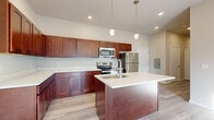 This thoughtfully designed 2-bedroom, 2-bathroom residence offers a functional and modern single-floor layout. The open-concept kitchen and living area serves as the heart of the home, showcasing rich dark cherry wood cabinetry, light quartz countertops, and a full suite of stainless steel appliances including a range, microwave, and refrigerator. A central kitchen island with an integrated sink and pendant lighting above adds both style and practicality, while recessed lighting and light hardwood-style flooring create a bright, cohesive atmosphere. Sliding glass doors in the living area provide natural light and access to a balcony.

Both bedrooms are carpeted and receive natural light through windows, offering a comfortable and quiet retreat. The primary bedroom is generously sized with dedicated closet space. The two bathrooms are finished with matching dark cabinetry and light countertops; one features a soaking tub and shower combination, while the other includes a walk-in shower stall. Hardwood-style flooring carries through both bathrooms. A hallway connects the living spaces to the private quarters, and in-unit washer and dryer hookups add everyday convenience. Two closets provide ample storage throughout.