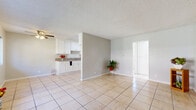 Located on Laurel Canyon Blvd in Los Angeles, this one-bedroom, one-bathroom unit offers a well-organized single-floor layout with a thoughtful mix of finishes throughout. The open living room welcomes natural light through dual windows and features warm beige tile flooring, a ceiling fan, and a wall-mounted A/C unit, creating a comfortable and functional common area. The kitchen is designed in a classic galley style, lined with crisp white cabinetry, granite-style countertops, and matching tile floors, offering ample storage and counter space for everyday cooking. A hallway connects the main living areas to the private bedroom, where light hardwood flooring, a ceiling fan, and a wide window add warmth and brightness. The bedroom is equipped with a full-width mirrored sliding closet, with two additional closets providing generous storage throughout the unit. The bathroom features a tub-shower combination adorned with elegant marble-style tile surround, a window for natural light, and a dark wood vanity for a refined finish. Textured ceilings are consistent throughout, adding a classic touch to the overall aesthetic of this practical and well-appointed Los Angeles residence.