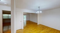Located at 1007 Hughes Dr in Trenton, NJ, this single-floor, two-bedroom, one-bathroom home offers a practical and well-organized layout. Warm hardwood flooring flows throughout the main living areas and bedrooms, lending a cohesive and inviting character to the space. The combined living and dining area is open and airy, connected by a wide passage and accented with a classic chandelier above the dining section. A sliding glass door in the living room fills the space with natural light and provides direct access to an outdoor area framed by lush greenery. The kitchen is equipped with ample honey-toned wood cabinetry, light countertops, and white appliances including a range, dishwasher, and refrigerator, all set on easy-to-maintain tile flooring. A windowed nook adjacent to the kitchen adds additional flexibility as a breakfast or utility area. Both bedrooms are comfortably sized, featuring the same warm hardwood floors, clean white walls, and natural light from windows. The primary bedroom offers generous proportions with closet access. The bathroom includes a full soaking tub with an overhead shower, surrounded by neutral beige tile — clean and functional in its design. Overall, this home presents a straightforward and well-maintained living environment.