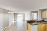 Located at 3149 151 Avenue NW in Edmonton, Alberta, this 2-bedroom, 2-bathroom unit offers a practical and well-organized single-floor layout. The open-concept living and dining area forms the heart of the unit, finished with light hardwood-style flooring throughout and neutral warm-toned walls that create a bright, cohesive feel. A pendant chandelier anchors the dining space, while a sliding glass door leads to a private balcony, filling the living area with natural light and providing outdoor views of the surrounding neighbourhood. The kitchen is efficiently designed with light maple cabinetry, dark laminate countertops, a double sink, and a full suite of white appliances including a refrigerator, electric range, and dishwasher. Track lighting overhead ensures excellent task illumination. The primary bedroom is generously sized, featuring a sliding door to the balcony and baseboard heating. The second bedroom receives natural light through a large window with neighbourhood views. Both bathrooms are clean and functional, each equipped with a tub-shower combination. Four closets throughout the unit provide ample storage. Textured ceilings are consistent throughout, adding a classic finishing detail to this well-maintained Edmonton residence.