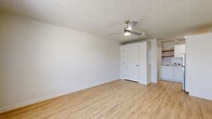 Located at 2050 State Highway 31 East in Athens, TX, this single-floor studio unit offers an efficient and well-designed layout that maximizes every square foot. The open living area features light-toned luxury vinyl plank flooring that runs throughout the space, contributing to a clean and cohesive aesthetic. Crisp white walls and a textured ceiling provide a bright, neutral backdrop, while a ceiling fan with an integrated light fixture keeps the space comfortable year-round. A wall-unit HVAC system ensures climate control, and a large window adjacent to the front entry door allows natural light to fill the room.

The kitchenette is neatly tucked toward the rear of the unit and includes white cabinetry, a stainless steel refrigerator, a sink, and additional counter space — offering functional utility within a compact footprint. Open shelving provides convenient storage options alongside the cabinetry.

The bathroom is finished with classic white tile surrounds on the tub-shower combination, mosaic tile flooring in warm neutral tones, a white vanity with a marble-patterned countertop, and brushed nickel fixtures throughout. A closet provides dedicated storage to complete the unit's practical layout. The overall ambiance is clean, minimal, and move-in ready.