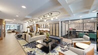 Located at 1031 N Vermont St in Arlington, Virginia, this thoughtfully designed amenity space spans a generous single floor, offering residents a refined and versatile environment for both relaxation and productivity. The main lounge area commands attention with its coffered ceiling detail and striking sculptural light fixtures — elongated brass-and-globe chandeliers that cast a warm, curated glow across the room. Plush neutral sofas, cognac leather accent chairs, and a bold abstract area rug anchor the central seating arrangement, creating an inviting social hub. A built-in workstation along a warm wood-paneled wall provides individual seating for focused work, complemented by a large display screen nearby. Adjacent, a glass-enclosed private office or conference room offers a quiet, professional setting with dark-toned flooring for contrast. The mailroom area features floor-to-ceiling parcel lockers framed by rich wood millwork, seamlessly integrated into the lounge's aesthetic. Herringbone-patterned light wood flooring flows through the corridors, connecting each zone with visual continuity. Curated artwork — including bold abstract canvases and whimsical portrait pieces — adds personality and character throughout. Large windows allow natural light to filter in, enhancing the space's bright, contemporary ambiance.