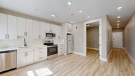 Located at 90 N Swan St in Albany, NY, this thoughtfully designed one-bedroom, one-bathroom unit offers a efficient and modern living experience across a single floor. Light-toned luxury vinyl plank flooring runs throughout, creating a cohesive and clean aesthetic.

The kitchen is a standout feature, showcasing white shaker-style cabinetry extending to the ceiling for ample storage, paired with quartz countertops featuring subtle marble veining. A full suite of stainless steel appliances — including a refrigerator, electric range, built-in microwave, and dishwasher — completes this functional cooking space. A glass tile backsplash and a window allowing natural light add to the kitchen's bright, welcoming atmosphere.

The bedroom is a cozy, well-proportioned retreat with neutral walls, wood-look flooring, and a wall-mounted mini-split HVAC unit for personalized climate control.

The bathroom is a true highlight, finished with dramatic floor-to-ceiling marble-look tile accented with gold veining. A walk-in rain shower with a linear drain, a warm wood-toned vanity with a white quartz countertop, and sleek matte black hardware lend the space a boutique hotel-inspired elegance. Recessed lighting throughout the unit enhances the clean, modern ambiance.