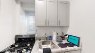 This well-appointed one-bedroom, one-bathroom unit offers a thoughtfully organized layout across a single floor. The living room serves as the central gathering space, showcasing warm parquet wood flooring laid in a classic basket-weave pattern that extends throughout the unit, lending a timeless character to the interior. Natural light enters through windows equipped with a wall-mounted air conditioning unit, complemented by a baseboard radiator for year-round climate control.

The kitchen is efficiently designed, featuring granite-style countertops, white shaker-style cabinetry, a stainless steel sink, and a gas range, providing all essential cooking amenities within a compact footprint. A window allows natural light into the space.

The bedroom is a comfortable, well-proportioned room with the same parquet flooring, a ceiling fan with light fixture, a window with an air conditioning unit, and access to a closet. A second closet provides additional storage elsewhere in the unit.

The bathroom includes a tub and shower combination with white tile surround and a vanity with matching cabinetry. Throughout the unit, white walls and clean lines create a bright, neutral ambiance.
