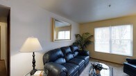 Located at 1493 Forest Brooke Way in Delaware, Ohio, this single-floor residence offers a practical and inviting layout designed for comfortable everyday living. The living area serves as the heart of the home, featuring neutral-toned walls and carpet flooring that create a warm, understated backdrop. Natural light filters in through multiple windows dressed with horizontal blinds, lending the space a bright and airy feel throughout the day. A wall-mounted mirror adds depth to the room, visually expanding the space, while there is ample room for furnishings and personal décor. The layout flows naturally, making the space both functional and easy to navigate. Subtle architectural details, including clean wall lines and a smooth ceiling, contribute to the home's tidy, well-maintained character. Greenery accents the interior, adding a touch of life and color against the neutral palette. The overall ambiance is calm and residential, suited to those seeking a straightforward, move-in-ready home in the Forest Brooke community of Delaware, Ohio — a city known for its welcoming neighborhoods and convenient access to local amenities.