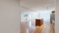 This thoughtfully designed 2-bedroom, 1-bathroom residence offers a functional and modern living experience across a single floor. The open-concept living and kitchen area is anchored by rich hardwood flooring that flows throughout, creating a warm and cohesive aesthetic. The kitchen is a standout feature, equipped with stainless steel appliances including a refrigerator, range, and microwave, complemented by warm wood cabinetry, a mosaic tile backsplash, granite countertops, and a generous island with seating — ideal for both cooking and entertaining. Track lighting overhead adds a modern, practical touch. The living area is bright and open, with clean white walls and recessed lighting that enhance the airy atmosphere. Both bedrooms are carpeted for comfort and finished with crisp white walls and ample natural light from large windows. The primary bedroom features dual sliding closets, offering generous storage. The bathroom continues the design consistency of the home, showcasing a wood vanity with granite countertop, a large mirror, and warm-toned flooring. A welcoming entrance completes this efficiently planned residence, making it a comfortable and stylish space suited for everyday living.