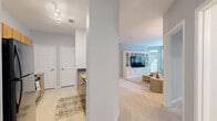 Located in Annapolis, MD, this single-floor residence offers three bedrooms and two full bathrooms within a thoughtfully designed layout. The living room serves as the heart of the home, bathed in natural light from a large multi-pane window and a glass door that opens to an outdoor balcony. A built-in white entertainment center adds both style and function, while soft carpeting and light blue-gray walls create a calm, coastal ambiance throughout.

The kitchen features warm wood cabinetry, granite countertops, and stainless steel appliances including a gas range, built-in microwave, and refrigerator. Light tile flooring and recessed lighting give the kitchen a clean, practical feel that flows into the adjacent hallway.

The primary bedroom is a comfortable retreat with two windows and direct balcony access, filling the room with natural light. A double-door closet provides ample storage, and soft carpeting extends throughout. The two bathrooms are finished with white vanities, large mirrors, and tile flooring; one features a walk-in glass shower, while the other includes a single-sink vanity. A carpeted hallway connects the bedrooms and bathrooms, maintaining a cohesive, tranquil aesthetic across the entire residence.