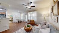 Located at 6301 Stonewood Dr in Plano, TX, this single-story 2-bedroom, 2-bathroom home offers a thoughtfully designed layout with comfortable living spaces throughout. The living room makes a welcoming first impression with rich wood-look flooring, crown molding, a ceiling fan, and large windows that allow natural light to fill the space. A gallery wall and generous seating area create an inviting, functional atmosphere.

The galley-style kitchen features warm honey-toned wood cabinetry lining both walls, stainless steel appliances including a refrigerator, microwave, dishwasher, and range, along with a double sink and light countertops. A dedicated laundry area is conveniently accessible from the kitchen corridor.

Both bedrooms are carpeted and well-sized, each equipped with a ceiling fan and windows dressed with sheer curtains that provide soft, diffused natural light. The primary bedroom offers a comfortable, serene retreat, while the second bedroom is equally bright and versatile. Each room is served by its own closet.

The two full bathrooms each include a tub-shower combination with clean white tile surrounds and wood-look flooring, providing a practical and tidy finish. The home also includes a hallway that connects the living areas to the private quarters, contributing to a clear and functional flow throughout the residence.