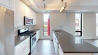This well-appointed 2-bedroom, 2-bathroom residence offers a thoughtfully designed single-level floor plan that balances comfort and functionality. The modern kitchen serves as a centerpiece, featuring crisp white cabinetry, sleek dark countertops, a large island with an undermount sink, stainless steel appliances including a gas range, microwave, and refrigerator, tile backsplash, and track lighting complemented by a stylish pendant fixture. Wood-style flooring runs throughout the main living areas, adding warmth to the contemporary aesthetic.

Each bedroom is generously sized, finished with plush carpeting and ceiling fans, and benefits from large windows that frame scenic urban and waterfront views. The bedrooms are complemented by well-organized walk-in closets with built-in shelving and hanging rods, providing ample storage.

The two bathrooms are finished with light tile flooring and neutral tones. The primary bathroom includes a glass-enclosed walk-in shower and a wide vanity with a white countertop, while the secondary bathroom features a soaking tub with shower combination. Both bathrooms are fitted with chrome fixtures and clean, minimalist finishes throughout.

Natural light flows generously through the large windows, enhancing the bright and airy atmosphere of the entire residence.