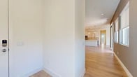 Located at 47432 Iris Way in La Quinta, California, this single-story home presents a clean, contemporary design throughout its well-appointed layout. The interior is characterized by light wood-look flooring that extends through the main living areas, crisp white walls, and recessed lighting that contributes to a bright, airy atmosphere.

The kitchen is a standout feature, showcasing a galley-style configuration with two-tone cabinetry — upper white cabinets paired with warm wood-toned lower cabinets — topped with white quartz countertops. A neutral-toned subway tile backsplash adds texture, while stainless steel appliances, including a gas range, microwave, and refrigerator, complete the space. A central island with an undermount sink provides additional prep and storage space.

The hallway leads to well-proportioned living areas, including a bedroom with plush neutral carpeting and a dedicated walk-in closet equipped with built-in hanging rods and shelving. An additional walk-in closet offers generous storage capacity.

The bathroom features white subway tile surrounding a soaking tub and shower combination, complemented by a wood-toned vanity with a white countertop and tile flooring. An attached garage with a concrete floor and roll-up door rounds out the functional amenities of this well-designed home.