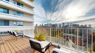 Located in the heart of Montréal's Golden Square Mile, this generously sized rooftop terrace at 1212 Avenue des Pins Ouest offers an impressive open-air amenity space with panoramic views of the city skyline. The deck is finished with warm-toned hardwood planking throughout, creating a cohesive and inviting atmosphere under the open sky.

The terrace is thoughtfully organized into several distinct zones, each designed to accommodate different uses. A large lounge area features a spacious sectional sofa arrangement with low coffee tables, ideal for relaxed gatherings. Adjacent to it, multiple dining tables and chair sets are positioned to take advantage of the surrounding views, making them well suited for al fresco meals or social events.

Tall planters filled with lush artificial hedge panels serve as natural-looking dividers throughout the space, providing privacy between zones while contributing a vibrant green aesthetic. Additional planters with seasonal foliage add color and texture throughout.

The perimeter of the terrace is enclosed by white railings, allowing unobstructed sightlines across the Montréal skyline, including views of downtown towers and the surrounding urban canopy. The surrounding brick and concrete residential buildings frame the space, reinforcing its elevated, urban character. The terrace is abundantly open to natural light, making it a bright and welcoming outdoor destination throughout the day.