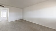 Located at 2035 Kings Hwy in Clearwater, Florida, this single-floor, 2-bedroom, 1-bathroom home offers a practical and comfortable layout. The interior is finished with neutral white walls and textured ceilings throughout, giving the space a clean, bright feel. Soft carpet covers the living room and both bedrooms, while wood-look vinyl flooring runs through the kitchen and additional areas, providing a pleasant contrast in materials. The living room is generously sized and connects seamlessly to the dining area, with natural light entering through front-facing windows and a glass-paneled door. Both bedrooms are well-proportioned with carpet flooring and natural light from multiple windows. The primary bedroom features a large louvered bifold closet, and the home is notably well-equipped with a total of six closets for ample storage. A hallway connects the bedrooms to the shared bathroom, which is a standout feature of the home — showcasing a full soaking tub surrounded by dramatic floor-to-ceiling grey marble-style wall panels. The kitchen is efficiently laid out in a U-shape, offering white lower cabinetry, warm wood upper cabinets, a double sink, electric cooktop, wall oven, and a full-size refrigerator, all complemented by a window that brings in natural light.