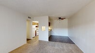 This single-floor residence offers a practical and comfortable layout designed for everyday living. The main living area combines carpet and hard-surface flooring, creating a clear visual distinction between relaxation and dining zones. A ceiling fan overhead provides year-round comfort, and a textured ceiling adds a classic touch throughout the space. A half-wall partition connects the living area to the kitchen, featuring a convenient pass-through counter with granite-style surfaces — ideal for casual dining or entertaining.

The galley-style kitchen is well-equipped with warm wood cabinetry, granite-patterned countertops, a double-basin stainless steel sink, and white appliances including a refrigerator and electric range. Light wood-look flooring runs through the kitchen, complementing the cabinetry tones and keeping the space bright and easy to maintain.

Two bedrooms are carpeted for comfort and each features sliding panel closet doors, offering ample storage. The bathroom presents a double-sink vanity topped with granite-style counters, accompanied by a well-lit mirror setup that enhances the sense of space. Overall, the residence delivers a functional, cohesive design with consistent finishes throughout.