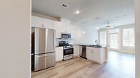 This thoughtfully laid-out one-bedroom, one-bathroom residence makes excellent use of its single-floor footprint, combining modern design with practical functionality throughout. The entrance welcomes you into an open, airy space highlighted by light-toned hardwood flooring that flows seamlessly through every room.

The kitchen is a standout feature, boasting tall white cabinetry, dark granite countertops, a classic subway tile backsplash, and a full suite of stainless steel appliances including a gas range, microwave, dishwasher, and refrigerator. Globe pendant lights hang above the peninsula, which doubles as a prep and dining area, while recessed lighting adds to the bright, clean aesthetic.

The living area is bathed in natural light, thanks to large windows dressed with horizontal blinds that offer both privacy and outdoor views. Neutral warm-toned walls complement the light flooring, creating a calm and inviting atmosphere.

The bedroom is a comfortable, well-proportioned space with its own window for natural light. Adjacent to the bedroom is a well-appointed bathroom featuring white cabinetry with dark granite countertops, a soaking tub with decorative tile surround, and direct access to a dedicated walk-in closet complete with hanging rods and shelving. A pantry provides additional storage convenience, rounding out this efficiently designed home.