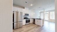 This thoughtfully laid-out one-bedroom, one-bathroom residence makes excellent use of its single-floor footprint, combining modern design with practical functionality throughout. The entrance welcomes you into an open, airy space highlighted by light-toned hardwood flooring that flows seamlessly through every room.

The kitchen is a standout feature, boasting tall white cabinetry, dark granite countertops, a classic subway tile backsplash, and a full suite of stainless steel appliances including a gas range, microwave, dishwasher, and refrigerator. Globe pendant lights hang above the peninsula, which doubles as a prep and dining area, while recessed lighting adds to the bright, clean aesthetic.

The living area is bathed in natural light, thanks to large windows dressed with horizontal blinds that offer both privacy and outdoor views. Neutral warm-toned walls complement the light flooring, creating a calm and inviting atmosphere.

The bedroom is a comfortable, well-proportioned space with its own window for natural light. Adjacent to the bedroom is a well-appointed bathroom featuring white cabinetry with dark granite countertops, a soaking tub with decorative tile surround, and direct access to a dedicated walk-in closet complete with hanging rods and shelving. A pantry provides additional storage convenience, rounding out this efficiently designed home.