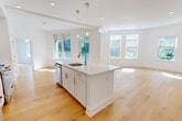 Located at 95 Fawcett St in Cambridge, MA, this thoughtfully designed 2-bedroom, 2-bathroom residence offers a bright and modern living experience across a single floor. The open-concept kitchen and living area serves as the heart of the home, anchored by a large center island with a quartz countertop, undermount sink, and pendant lighting overhead. White shaker cabinetry pairs with stainless steel appliances, including a gas range, built-in microwave, and French door refrigerator, complemented by a subtle tile backsplash. Warm-toned hardwood floors extend throughout the entire residence, enhancing the clean, contemporary aesthetic. Large windows flood the living area with natural light and offer views of the surrounding neighborhood. The spacious primary bedroom features multiple windows, generous closet space, and its own well-appointed en-suite bathroom with a walk-in shower. The second bedroom is equally well-lit with access to a full bathroom featuring a tub-shower combo and light tile flooring. Both bathrooms are finished with white cabinetry and clean, modern fixtures. Additional closets provide ample storage. The living area opens to views of the vibrant Cambridge streetscape, making this a well-connected urban residence.