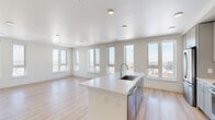 Located in Denver's vibrant Five Points neighborhood, this modern 2-bedroom, 2-bathroom residence offers a bright and thoughtfully designed single-floor layout. The open-concept kitchen and living area serves as the heart of the home, anchored by a large center island with a white quartz countertop and undermount sink. The kitchen is fully equipped with stainless steel appliances, including a French door refrigerator, range, and built-in microwave, complemented by sleek gray cabinetry that extends to the ceiling. Light hardwood flooring flows throughout the main living areas, enhancing the clean, contemporary aesthetic. A wall of oversized windows fills the living space with natural light and frames sweeping panoramic views of the Denver cityscape. Both bedrooms are generously sized and feature plush carpeting and ceiling fans. The primary bedroom is spacious and connects to a well-appointed en-suite bathroom complete with a dual-sink vanity, white quartz countertops, and ample cabinetry. A second full bathroom serves the additional bedroom. Each bedroom also benefits from dedicated closet space. The overall ambiance is modern and airy, defined by neutral tones, clean lines, and abundant natural light paired with elevated urban views.
