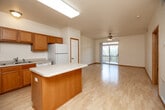 This single-floor, one-bedroom, one-bathroom unit offers a functional and comfortable layout designed to maximize every square foot. The open-concept kitchen is a standout feature, equipped with warm oak cabinetry, white appliances including a refrigerator, range, microwave, and dishwasher, and a central island with a light countertop that provides additional prep and seating space. Light hardwood-style flooring runs throughout the kitchen and living areas, adding warmth and continuity.

The spacious living room is filled with natural light streaming through a sliding glass door that opens onto a private balcony with outdoor views of surrounding trees, creating a bright and airy atmosphere. A ceiling fan overhead enhances comfort throughout the space.

The bedroom is generously sized, featuring plush carpet, a ceiling fan with light fixture, and a large window that continues to bring in natural light and outdoor views. The room includes access to a dedicated closet fitted with wire shelving for organized storage.

The bathroom is finished with neutral tile flooring, an oak vanity with sink, and a well-lit mirror. Throughout the unit, six-panel doors with oak trim provide a cohesive, classic aesthetic that ties each room together.