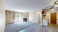 Located at 426 W Lake Lansing Rd in East Lansing, MI, this one-bedroom, one-bathroom unit offers a practical and comfortable layout across a single floor. The galley-style kitchen is well-equipped with warm wood cabinetry lining both walls, ample counter space with light-colored laminate surfaces, a double-coil electric range, refrigerator, and a stainless steel sink — all set atop durable wood-look flooring. A textured ceiling runs throughout, adding a classic residential character to the space. The combined kitchen and living area transitions into a spacious, carpeted living room that serves as the heart of the home. This room features a wood-burning fireplace with a clean white mantle, a wall-mounted air conditioning unit, a baseboard heating system, and a sliding glass door that opens to a private balcony overlooking a wooded outdoor setting. The bedroom is generously proportioned, featuring plush carpeting, a ceiling fan with light fixture, natural light from a large window with vertical blinds, and dual closets with wood-paneled bifold doors providing excellent storage. The full bathroom includes a vanity with wood cabinetry and light countertop, a shower-tub combo, and wood-look tile flooring with baseboard heating.