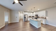 Located in Austin's vibrant 78702 zip code, this well-appointed single-story home offers a thoughtfully designed open-concept layout. The combined kitchen and living area serves as the heart of the home, featuring rich wood-look flooring, recessed lighting, and a ceiling fan that keeps the space comfortable year-round. The kitchen is a standout, showcasing crisp white shaker cabinets with matte black hardware, a neutral tile backsplash, quartz countertops, a central island with an undermount sink, and a full suite of stainless steel appliances. Natural light pours into the living room through tall windows and a glass-paneled door that opens to an outdoor area. A clean hallway connects the main living space to the private quarters. Both bedrooms are carpeted for warmth and comfort, with ceiling fans and windows that invite natural light. One bedroom features built-in open shelving, adding practical storage and display space. The full bathroom is finished with white vertical subway tile in the tub/shower surround, matte black fixtures, a white vanity, and a large mirror framed in black. A dedicated closet completes the functional layout of this clean, modern Austin home.