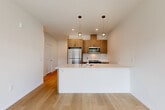 Located at 2104 172nd St NE in Marysville, WA, this well-designed one-bedroom, one-bathroom unit offers a thoughtful layout across a single floor. The open-concept living area seamlessly integrates the kitchen, dining, and living spaces, creating an inviting and functional hub. The kitchen features warm wood cabinetry, white quartz countertops, a peninsula with an undermount sink, subway tile backsplash, stainless steel appliances, and stylish pendant lighting overhead. Light hardwood-style flooring flows throughout the main living areas, enhancing the bright, airy atmosphere. A dedicated den provides flexible space suitable for a home office or additional living area. The bedroom is carpeted for comfort and is served by natural light through a wide window with views of the surrounding neighborhood. A generous walk-in closet with wire shelving offers ample storage, complemented by a total of five closets throughout the unit. The full bathroom is finished with a wood-toned vanity, white countertop, and a clean tub-shower combination. A private balcony extends the living space outdoors. The hallway connects all areas efficiently, and the entrance provides a welcoming transition into the home.