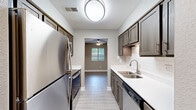 Located at 4256 Oak Forest Ct SE in Kentwood, Michigan, this well-appointed 2-bedroom, 2-bathroom single-floor home offers a thoughtfully designed layout with modern finishes throughout. The galley-style kitchen is a standout feature, showcasing rich dark-toned cabinetry, crisp white quartz countertops, a classic subway tile backsplash, and a full suite of stainless steel appliances including a refrigerator, electric range, dishwasher, and microwave. Light hardwood-style flooring runs through the main living areas, complementing the neutral warm-gray walls that create a cohesive and contemporary feel. The living room and dining area provide comfortable gathering spaces, while natural light filters in through windows dressed with horizontal blinds. The primary bedroom offers a generous footprint with plush carpeting, a ceiling fan, and a large window with outdoor views. The second bedroom also features carpeting and natural light. A walk-in closet with dual shelving rods provides ample storage. Both bathrooms are finished with dark wood vanities and white countertops, consistent with the home's design palette. A dedicated laundry area houses a stacked Whirlpool washer and dryer unit for added convenience. The overall ambiance is clean, modern, and move-in ready.