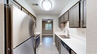Located at 4256 Oak Forest Ct SE in Kentwood, Michigan, this well-appointed 2-bedroom, 2-bathroom single-floor home offers a thoughtfully designed layout with modern finishes throughout. The galley-style kitchen is a standout feature, showcasing rich dark-toned cabinetry, crisp white quartz countertops, a classic subway tile backsplash, and a full suite of stainless steel appliances including a refrigerator, electric range, dishwasher, and microwave. Light hardwood-style flooring runs through the main living areas, complementing the neutral warm-gray walls that create a cohesive and contemporary feel. The living room and dining area provide comfortable gathering spaces, while natural light filters in through windows dressed with horizontal blinds. The primary bedroom offers a generous footprint with plush carpeting, a ceiling fan, and a large window with outdoor views. The second bedroom also features carpeting and natural light. A walk-in closet with dual shelving rods provides ample storage. Both bathrooms are finished with dark wood vanities and white countertops, consistent with the home's design palette. A dedicated laundry area houses a stacked Whirlpool washer and dryer unit for added convenience. The overall ambiance is clean, modern, and move-in ready.