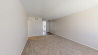 This two-bedroom, two-bathroom single-floor residence in Shreveport, Louisiana offers a straightforward and functional layout designed for comfortable everyday living. The living areas feature neutral-toned carpet and textured ceilings, creating a clean and understated aesthetic throughout. Two living room spaces provide flexibility for both relaxing and dining, with natural light filtering in through blinds-covered windows.

The galley-style kitchen is efficiently designed, featuring white cabinetry, speckled laminate countertops, a stainless steel sink, and white appliances including a refrigerator and electric range. A window above the counter allows natural light to brighten the workspace. Wood-look flooring runs through the kitchen and connecting hallway, adding a warm contrast to the neutral walls.

Both bedrooms are carpeted and include a notable painted brick accent wall, lending a subtle textural element to the rooms. Each bedroom is served by its own closet for added storage convenience. The bathrooms are well-appointed, with one featuring a white vanity with a speckled countertop and a framed mirror with overhead lighting, and the other showcasing a tiled tub-shower combination with a decorative gold arabesque border accent. The hallway connecting the main areas features dark wood-look flooring and leads seamlessly between the kitchen and living spaces.