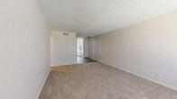 This two-bedroom, two-bathroom single-floor residence in Shreveport, Louisiana offers a straightforward and functional layout designed for comfortable everyday living. The living areas feature neutral-toned carpet and textured ceilings, creating a clean and understated aesthetic throughout. Two living room spaces provide flexibility for both relaxing and dining, with natural light filtering in through blinds-covered windows.

The galley-style kitchen is efficiently designed, featuring white cabinetry, speckled laminate countertops, a stainless steel sink, and white appliances including a refrigerator and electric range. A window above the counter allows natural light to brighten the workspace. Wood-look flooring runs through the kitchen and connecting hallway, adding a warm contrast to the neutral walls.

Both bedrooms are carpeted and include a notable painted brick accent wall, lending a subtle textural element to the rooms. Each bedroom is served by its own closet for added storage convenience. The bathrooms are well-appointed, with one featuring a white vanity with a speckled countertop and a framed mirror with overhead lighting, and the other showcasing a tiled tub-shower combination with a decorative gold arabesque border accent. The hallway connecting the main areas features dark wood-look flooring and leads seamlessly between the kitchen and living spaces.