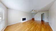 This two-floor home offers a functional and well-organized layout with consistent finishes throughout. The main level is anchored by a spacious living area featuring warm hardwood flooring, a ceiling fan with light fixture, and a classic white brick fireplace that serves as a focal point. Natural light filters in through windows flanking the front entry, and a staircase leads to the upper floor. An adjacent open area provides additional living or dining space, also finished with hardwood floors and access to the outdoors via sliding glass doors.

The galley-style kitchen is efficiently designed with white cabinetry, light countertops, a stainless steel sink, and white appliances including a refrigerator and electric range. The hardwood flooring continues seamlessly into the kitchen.

Two bathrooms serve the home — one featuring a tub-shower combination and hardwood flooring, and another with a vanity, light countertop, mirror, and hardwood floors.

The upper level hosts carpeted bedrooms, each equipped with a ceiling fan and French-style doors that open to the outdoors, providing natural light and ventilation. One bedroom features a wall of sliding closet doors, offering generous storage. The neutral palette and clean finishes throughout create a bright, move-in-ready environment.