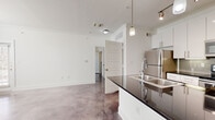 This single-story, one-bedroom, one-bathroom unit offers a thoughtfully designed layout with a consistent modern aesthetic throughout. Polished concrete floors extend across all living areas, providing a sleek, industrial character that unifies the space.

The open-concept living area features multiple windows and a glass-paned exterior door that invite abundant natural light, creating a bright and airy atmosphere. A ceiling fan adds both function and comfort to the main living zone.

The kitchen is well-appointed with white shaker-style cabinetry extending to the ceiling, dark granite countertops, a gray subway tile backsplash, and a full suite of stainless steel appliances, including a refrigerator, electric range, microwave, and dishwasher. A peninsula with an undermount sink provides additional prep and casual dining space.

The bedroom accommodates a comfortable layout, benefits from natural light via double windows, and includes a ceiling fan. A dedicated closet provides storage, and the room connects conveniently to the rest of the unit.

The bathroom features large-format white tile surrounding a soaking tub with an overhead shower, white cabinetry with brushed nickel hardware, a dark granite vanity top, and a vessel sink. A dedicated laundry room with washer and dryer hookups completes this efficiently organized unit.